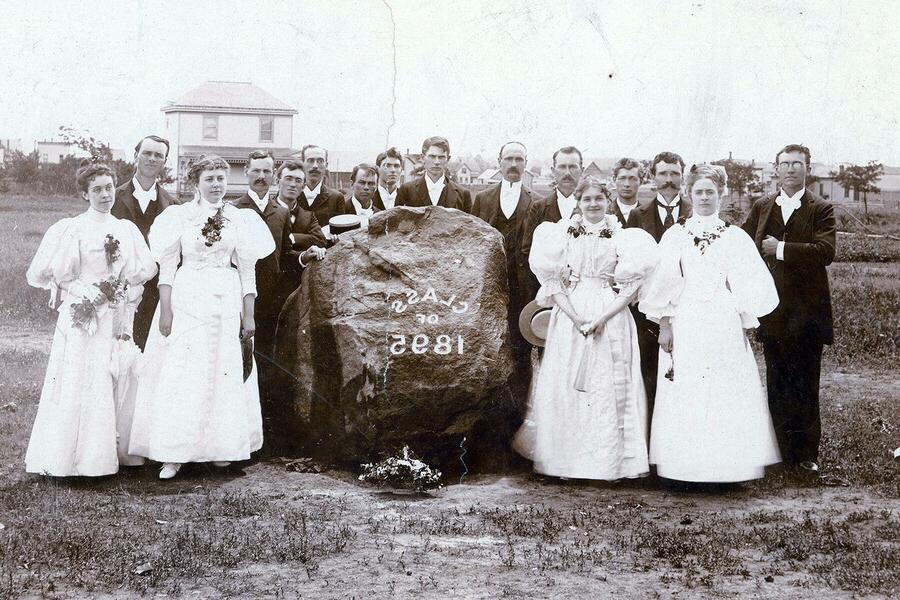 1895年的班级里有四个女生站在一块大石头周围，男生站在石头后面. 